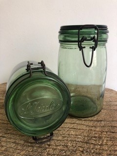 2 bocaux en verre teinté vert avec une fermeture à clip en fer. L'un des 2 est couché avec une inscription sur le dessus
