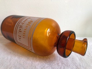 Un vieux flacon pharmacologique en verre marron a une inscription latine sur fond blanc est couché